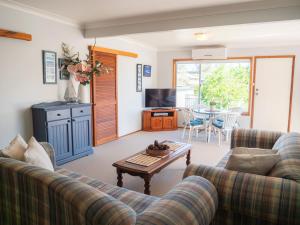 ein Wohnzimmer mit zwei Sofas und einem Tisch in der Unterkunft Collingwood Beach Cottage - Belle Escapes Jervis Bay in Vincentia