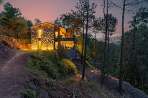 a house on a hill with lights on it at SaffronStays The Hill Abode in Kasauli