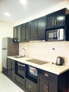 a kitchen with black cabinets and a sink and microwave at Kosmos Phu Quoc Apart Hotel in Phu Quoc