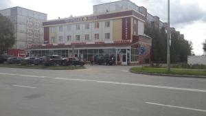 a large building with cars parked in a parking lot at Cherniy Mys Hotel in Surgut