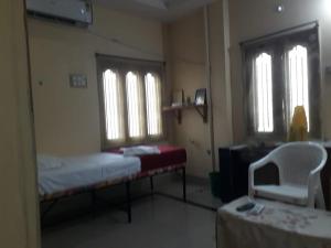 a room with two beds and a chair and two windows at Kodali Homestays in Bhadrāchalam