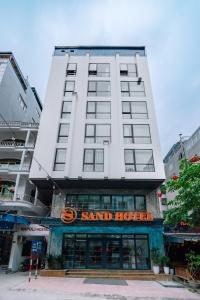 a tall white building with a sign on it at Sand Hotel in Cat Ba