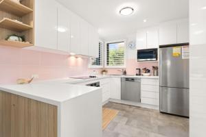 a kitchen with white cabinets and a stainless steel refrigerator at Inish by Experience Jervis Bay in Huskisson +12 photos