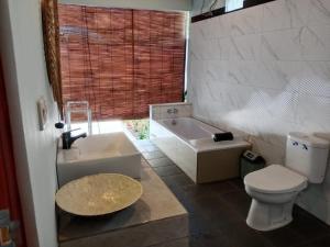 a bathroom with a tub and a toilet and a sink at Private Villa Aditya Beach in Buleleng