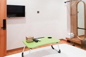 una mesa verde en una habitación con TV en Urbanview Hotel R House Batuaji en Kubuk