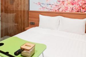 ein weißes Bett mit einem grünen Tablett mit Fernbedienung in der Unterkunft Urbanview Hotel R House Batuaji in Kubuk