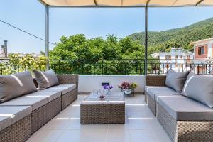 a patio with couches and a table on a balcony at Forest view villa Skopelos in Skopelos Town
