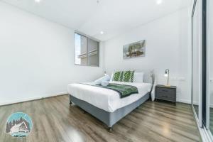 een witte slaapkamer met een bed en een raam bij Aircabin - Burwood - Modern Comfy - 2 Beds Apt in Sydney