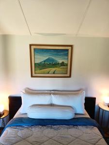 a bedroom with a bed with a painting on the wall at VILLACANTIK Yogyakarta triple bed for six persons in Bantul