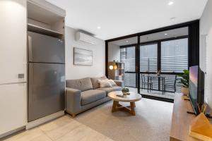 uma sala de estar com um sofá e uma mesa em Sleek Inner-City 1-Bed Pad with Pool & BBQ em Melbourne