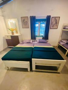 - une chambre avec 2 lits et une fenêtre avec des rideaux bleus dans l'établissement Eagles view Gongala, à Deniyaya