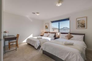 um quarto com 2 camas, uma secretária e uma janela em StayAU Cozy Holiday House 4BRM Big Group Tarneit em Tarneit
