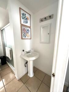 a white bathroom with a sink and a mirror at Modern Apartment near Disneyland & DTLA in Bellflower