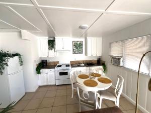 cocina con armarios blancos, mesa y sillas en Modern Apartment near Disneyland & DTLA, en Bellflower