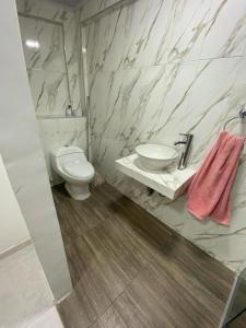 a white bathroom with a toilet and a sink at 2 HABITACIONES EN CASA CAMPO GUACOCHE - 8PERSONAS A 12 MINUTOS DE VALLEDUPAR, CERCA PARQUE DE LA LEYENDa in Valledupar