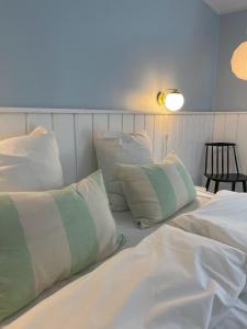 ein Bett mit weißer Bettwäsche und Kissen darauf in der Unterkunft Egn Boutique Hotel in Stege