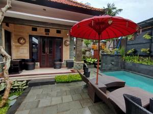 un patio con una sombrilla roja junto a la piscina en Meliora bali villa, en Ubud