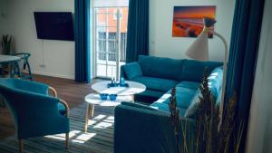 ein Wohnzimmer mit einem blauen Sofa und Stühlen in der Unterkunft Plesners Badehotel-Lejligheder in Skagen