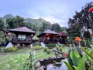 a couple of cottages with a pond in front at Sembalun Kita Cottage in Sembalun Lawang
