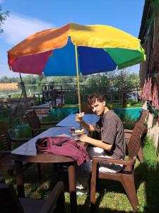 a man sitting at a table under an umbrella at LakeSide Homestay Srinagar in Srinagar