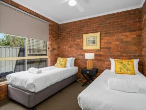 twee bedden in een kamer met een bakstenen muur bij Beautiful Bala in Shepparton