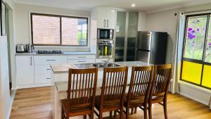 a kitchen with a table and chairs and a refrigerator at Charming Riverside Retreat sleep6 in Dora Creek