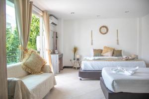 a bedroom with two beds and a couch and a window at Kata Station Boutique Hotel in Kata Beach