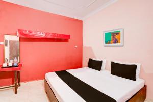 OYO Hotel Abhilasha في Bhilai: غرفة حمراء فيها سرير وجدار احمر