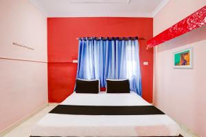 OYO Hotel Abhilasha في Bhilai: غرفة نوم بسرير وجدار احمر