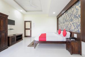 印多爾的住宿－OYO HOTEL SHOOLIN，一间卧室配有一张带红色枕头的大床
