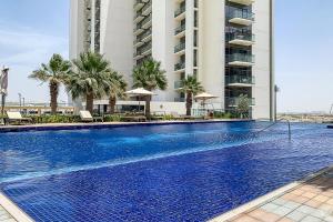 a large swimming pool with palm trees and a building at Frank Porter - Golf Vita in Dubai Marina