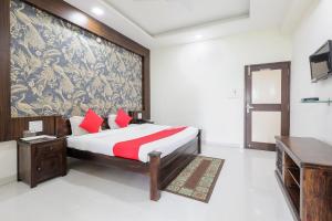 a bedroom with a large bed with red pillows at OYO HOTEL SHOOLIN in Indore