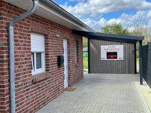 un edificio de ladrillo con un garaje con un cartel. en Ferienhaus "Golden Delicious" Meppen Ebenerdig Carport Terrasse Neubau NETFLIX Free WIFI 2 Schlafzimmer Küche GästeWC en Meppen