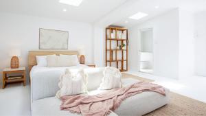 a white bedroom with a bed and a couch at Bungalow 21 in Callala Beach
