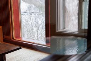 una bañera en una habitación junto a una ventana en 志賀高原 白い温泉 渓谷の湯, en Yamanouchi