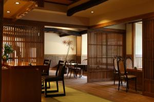 a dining room with wooden chairs and a table and a table and chairsktop at 志賀高原 白い温泉 渓谷の湯 in Yamanouchi