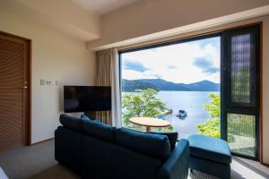 a living room with a couch and a large window at Hakone Hotel in Hakone