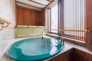 a large bath tub in a room with a window at 志賀高原 白い温泉 渓谷の湯 in Yamanouchi
