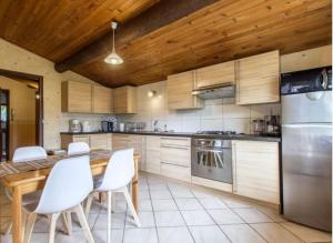 eine Küche mit weißen Stühlen und einer Holzdecke in der Unterkunft Appartement les Nattes in Passy