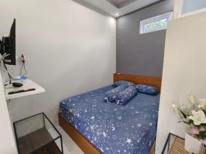 1 dormitorio con 1 cama con sábanas y almohadas azules en Pelemsewu Living Homestay Jogja, en Jarakan