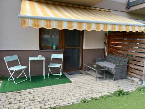un patio con 2 sedie, un tavolo e un tendone di Veresegyház Relax Apartman a Veresegyház