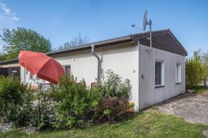 a small house with a red umbrella in front of it at Strandnaher Bungalow in Dierhagen