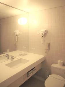 ein Badezimmer mit einem Waschbecken, einem WC und einem Spiegel in der Unterkunft Hoshino Resorts RISONARE Guam in Tamuning