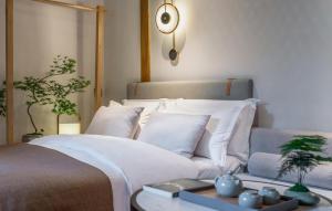 um quarto com uma cama com almofadas brancas e uma mesa em Xinxiang Yayuan Beijing Sihe courtyard with sky garden terrace Near Tiananmen Square Forbidden City Wangfujing Pedestrian Street and the subway em Pequim