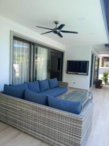a living room with a blue couch and a ceiling fan at Zensiri pool villa Koh Chang in Ko Chang