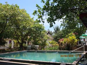 a swimming pool in front of a house with trees at Bohemiaz Resort and Spa Kampot in Kampot