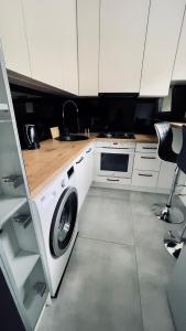 cocina con armarios blancos, lavadora y secadora en Przytulne mieszkanie Jarzębinka en Gdansk
