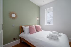ein Schlafzimmer mit einem weißen Bett mit rosa und weißen Kissen in der Unterkunft GuestReady - Chic in the heart of Kensington in London