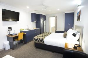 1 dormitorio con cama, escritorio y cocina en Altitude Motel Apartments, en Toowoomba
