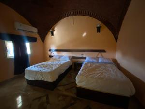 Mandīshah的住宿－Oasis inn House，两张床位于带拱门的房间里